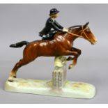 A Beswick equestrian figure of a woman riding side saddle on a bay horse vaulting a fence.