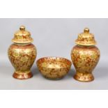 A pair of decorative Chinese lidded baluster mounted vases and a bowl decorated in gilt on red