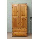 A pine two door single wardrobe over two drawer storage base.