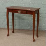 A modern hall table incorporating a single drawer raised on cabriole supports.