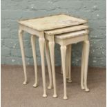 A nest of three cream painted tables with pastel floral design.