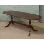 An oval coffee table on twin pedestal supports.