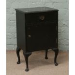 A black painted single drawer bedside cabinet raised on cabriole legs.