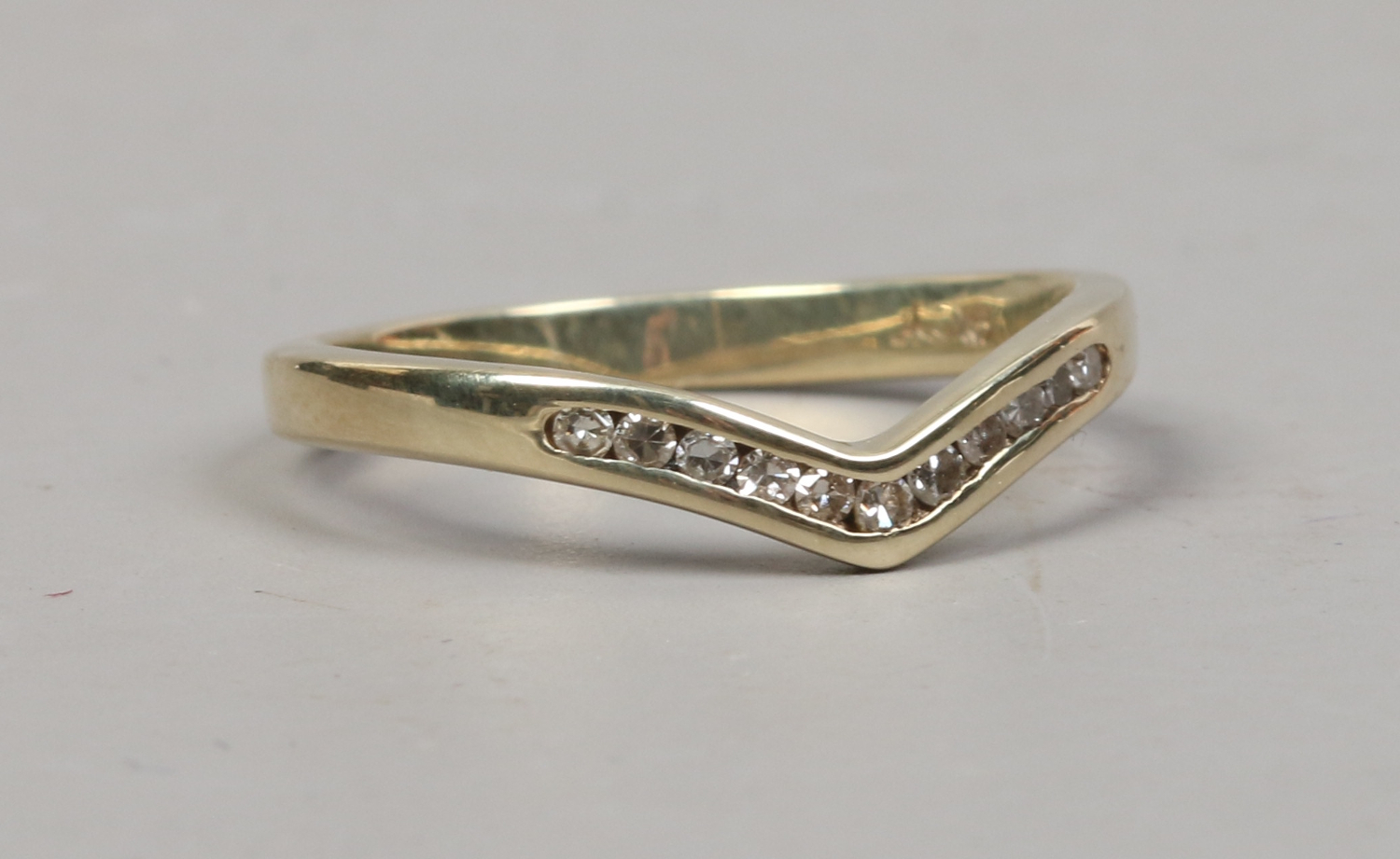 A 9ct gold channel set diamond wishbone ring size K