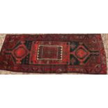 A large red ground Persian runner with strong rich colours and unique design, 296 x 120cm.