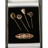 Four gold stick pins including two gem set and a pierced 9ct gold sweetheart brooch.