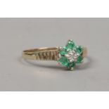 A 9ct gold emerald and diamond cluster ring with stepped shoulders size L