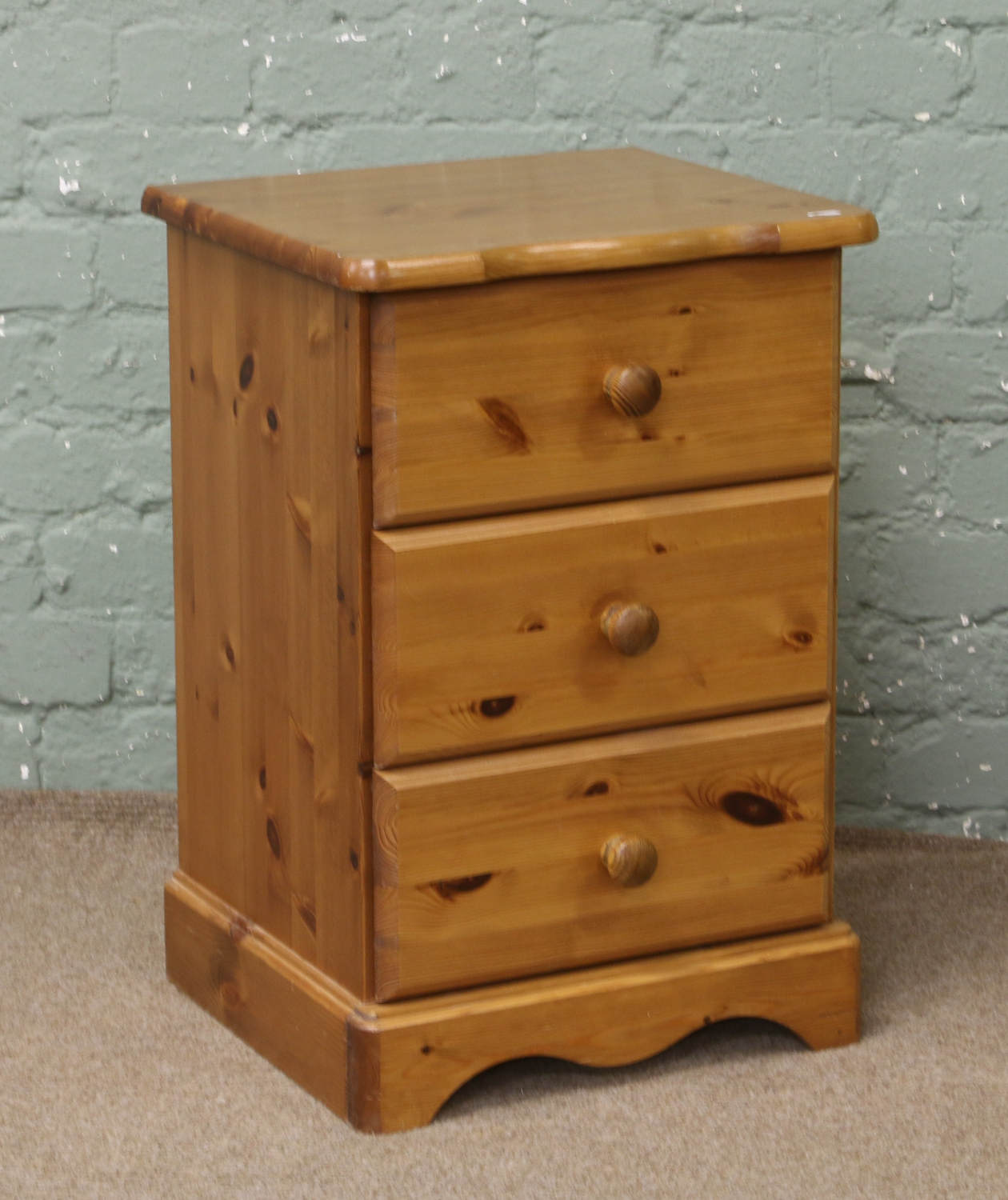 A pine three drawer bedside chest.