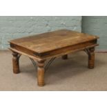 A hardwood coffee table with metal mounts, raised on turned supports.