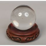 A crystal ball raised on a Chinese carved hardwood stand.