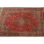 A red ground Persian Mashad carpet with traditional medallion design, 335 x 235cm.