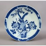 A Chinese charger painted in underglaze blue with a peacock in a landscape with peonies.