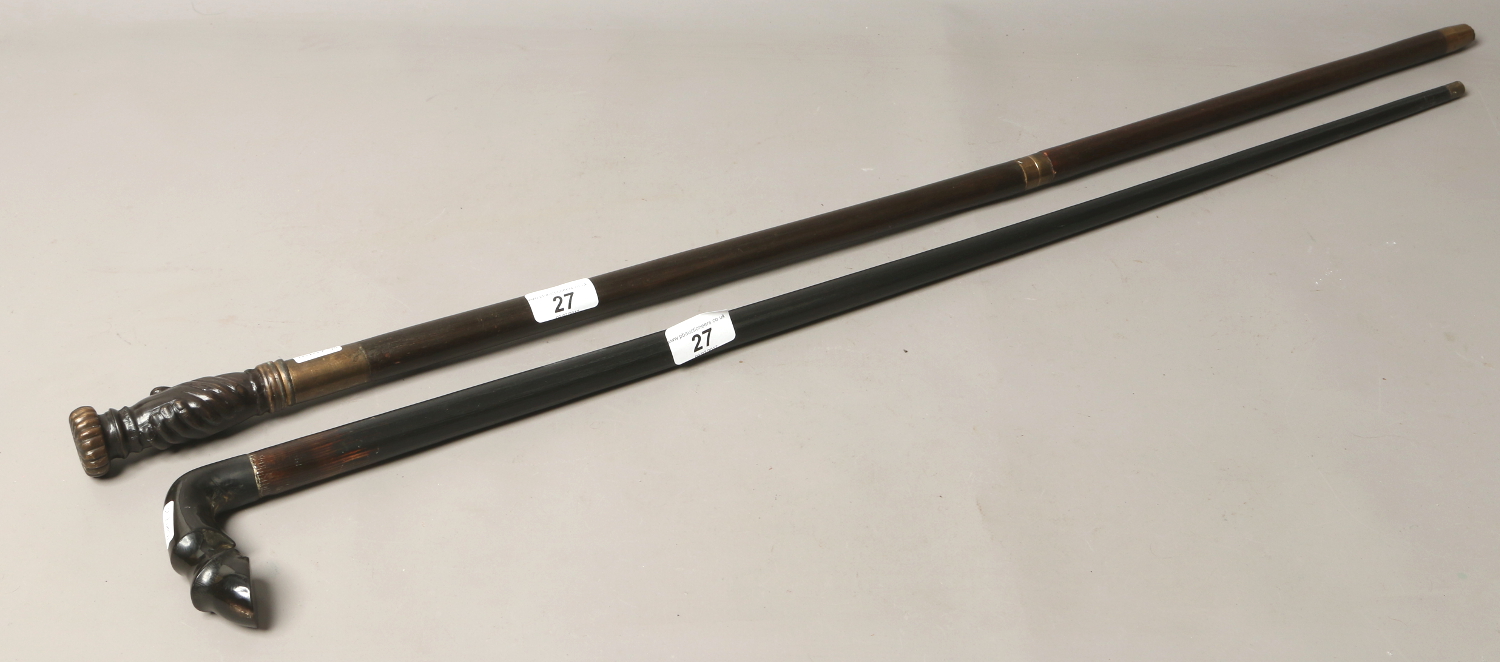 Two hardwood walking sticks one formed with a horses hoof handle the other with shaking hands.