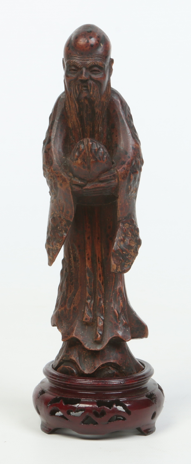 A 19th century Chinese carved and stained wood figure of a sage raised on associated carved