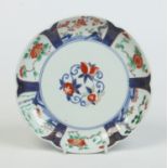 A Japanese six lobed Imari dish painted to the centre with peaches and pomegranates under a