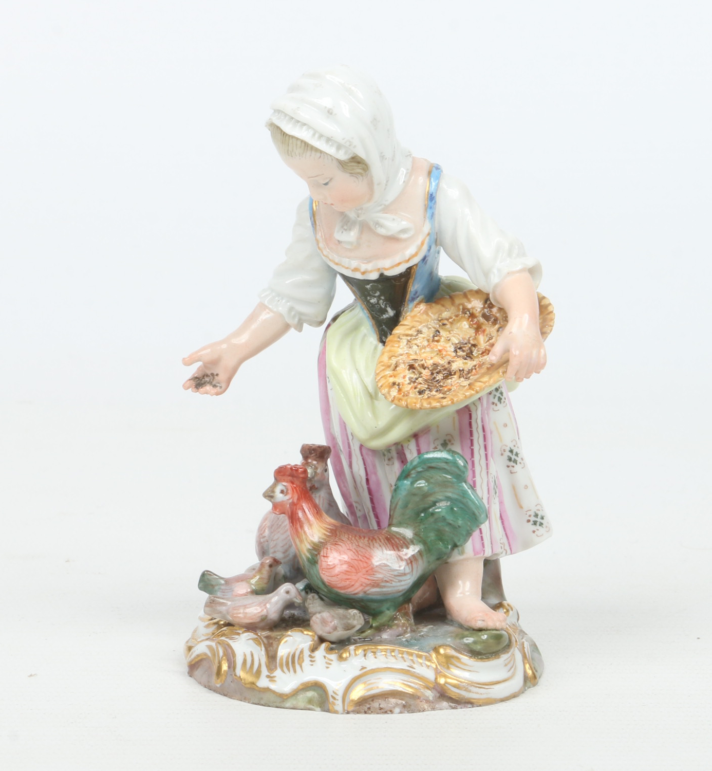 A 19th century Meissen figure formed as a young rural girl feeding chickens.