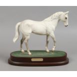A Beswick model of a horse titled Desert Orchid, matt white on wooden plinth.