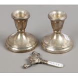 A pair of hallmarked silver dwarf candlesticks along with a silver and mother of pearl babies