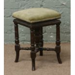 A Victorian adjustable piano stool raised on turned supports with screw mechanism.