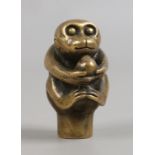 A brass cane topper formed as a monkey holding a nut.