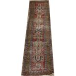 An antique wool carpet runner decorated with geometric patterns 255 x 58cm.