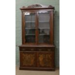 A Victorian carved mahogany bookcase with burr walnut panelled cupboard doors.