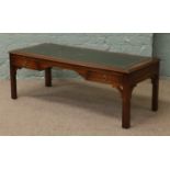 A carved mahogany coffee table with green leather inset top and two magazine drawers raised on