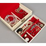A cream jewellery box and contents of costume jewellery including earrings, necklaces, brooches etc,