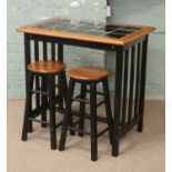 A modern designer style tiled top breakfast bar and two matching bar stools.