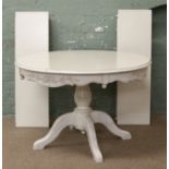 A white painted extending circular dining table along with four white painted rush seat chairs.