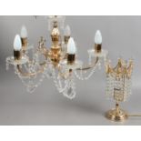 A five branch brass effect chandelier with cut glass droplets, along with a similar tablelamp.