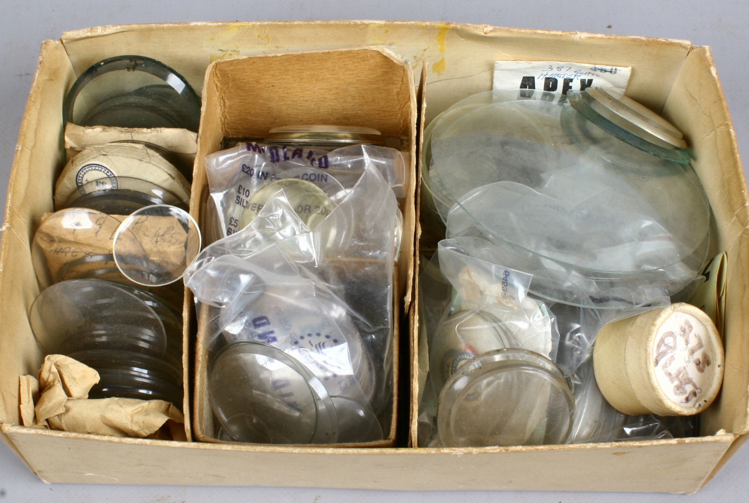 A collection of watch glasses for spares and repairs.