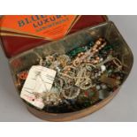 A vintage tin and contents of costume jewellery including badges, necklaces, brooches,