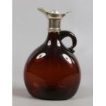 An amber glass claret jug with loop handle and white metal mounts.