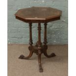 A Victorian octagonal occasional table raised over triple reeded column legs.