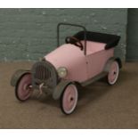A childs vintage pedal car (headlight missing).