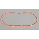 A string of pale pink coral beads each carved on the form of a tulip.