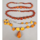 Two strings of amber coloured bakelite beads along with an amber necklace.