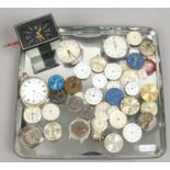 A tray to include Jaeger transistor car dash clock, pocket watches, watch movements and dials.