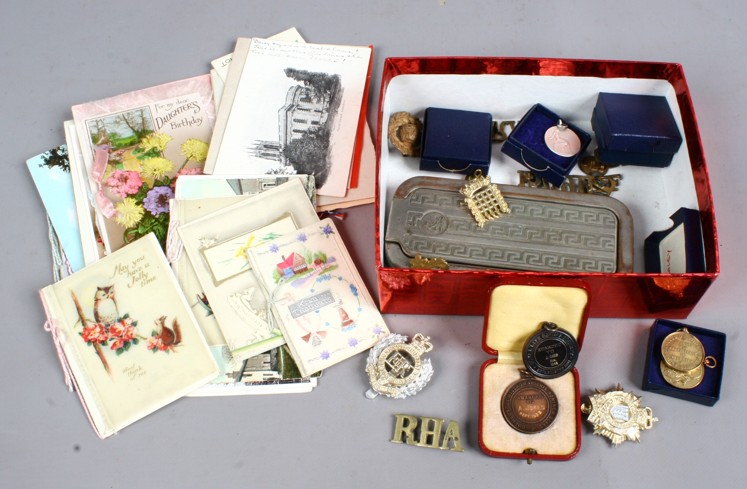 A box of various miscellaneous to include postcards, military badges,