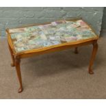 A glass top coffee table decorated with world bank notes and raised on cabriole legs.