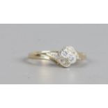 A 9ct gold crossover ring set with a pair of brilliant cut diamonds and with diamonds set shoulders,