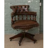 A brown deep buttoned leather captains swivel chair raised on castered feet.