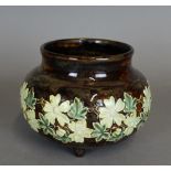 A Doulton stoneware Cauldron shaped vase, moulded with a band of white flowers on a brown ground,