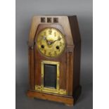 An early 20th Century walnut and brass mantel clock of Arts & Crafts architectural design, with