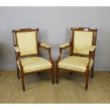 A pair of Edwardian inlaid satinwood open armchairs, with carved leaf capped finials, upholstered in