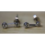 A pair of 18ct white gold and diamond drop earrings, the larger stone suspended by a bar, weight 0.