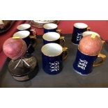 8 blue and gilt pottery mugs bearing English 3 lions, ebonised plinth surmounted by 3 broken