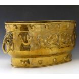 Embossed brass oval log bin with lion mask ring handles, length 59cm.