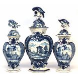 Matched garniture of three Delft lidded vases, with bird finials, the hexagonal bodies painted